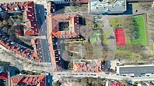 Aerial shot of european city sports grounds in residential area and sloped tiled roofs of the dwelling buildings, top