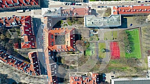 Aerial shot of european city sports grounds in residential area and sloped tiled roofs of the dwelling buildings, top