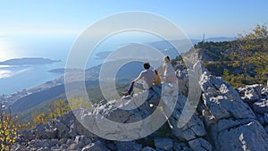 Aerial shot. Family of toursts father mother and son visit the Fortress Kosmach in Montenegro. Drone rotates around them