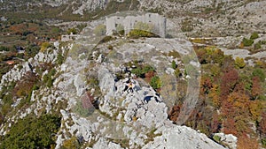 Aerial shot. Family of toursts father mother and son visit the Fortress Kosmach in Montenegro. An old fortress built by