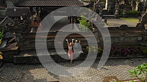 Aerial shot of the family travelers sitting in a stairs of the Pura Gunung Lebah temple in Ubud on the Bali island