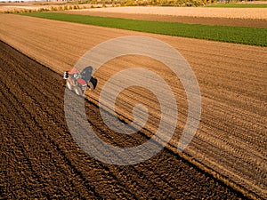 Aerial shot of a farmer plowing stubble field