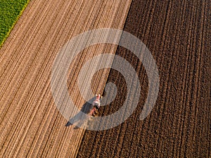 Aerial shot of a farmer plowing stubble field