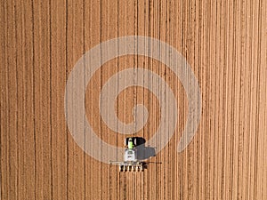 Aerial shot of a farmer seeding, sowing crops at field.