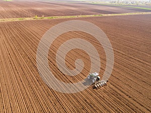 Aerial shot of a farmer seeding, sowing crops at field.