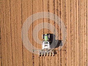 Aerial shot of a farmer seeding, sowing crops at field.