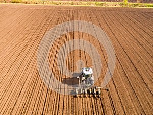 Aerial shot of a farmer seeding, sowing crops at field.