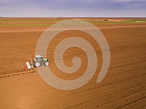 Aerial shot of a farmer seeding, sowing crops at field.