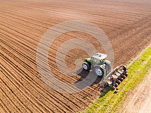 Aerial shot of a farmer seeding, sowing crops at field.