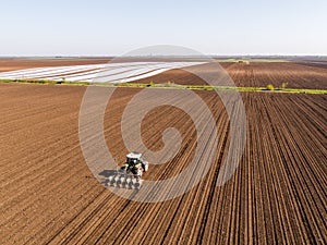 Aerial shot of a farmer seeding, sowing crops at field.