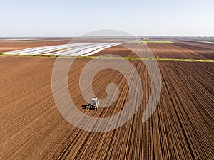 Aerial shot of a farmer seeding, sowing crops at field.