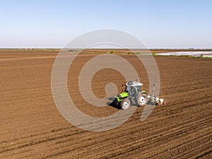 Aerial shot of a farmer seeding, sowing crops at field.