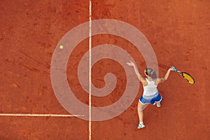 Aerial shot of a female tennis player on a court during match. Young woman playing tennis.High angle view.