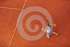 Aerial shot of a female tennis player on a court during match. Young woman playing tennis.High angle view.