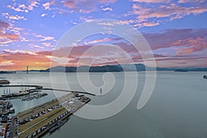 aerial shot of the Fisherman\'s wharf, Aquatic Cove, the Golden Gate Bridge over the ocean water, mountain ranges and docked