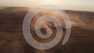 Aerial shot: flying around combines harvesting an summer sunset