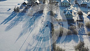 Aerial shot following car driving through residential area in snow covered winter