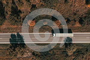 Aerial shot of freight transportation truck on road in summer afternoon, top down drone image