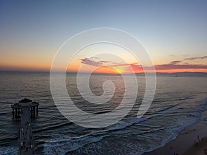 An aerial shot of a gorgeous summer landscape at the Manhattan Beach Pier with a stunning sunset in the sky