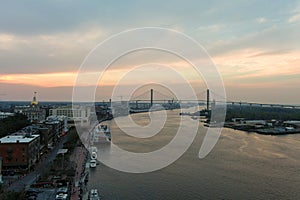 aerial shot of a gorgeous sunset over the Savannah River with Talmadge Memorial Bridge, hotels, restaurants and bars and shops