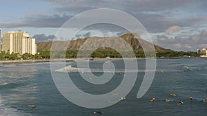 Aerial shot of a group of surfers riding a wave in Waikiki Beach with Diamond Head in the background