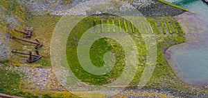 Aerial shot of the harbor embankment of Vlissingen, stones covered in green seaweed with ship anchor decorations, dutch landscape