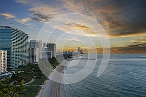 aerial shot of hotels, luxury condos and skyscrapers along the coastline at sunrise at Bal Harbour Beach, blue ocean water