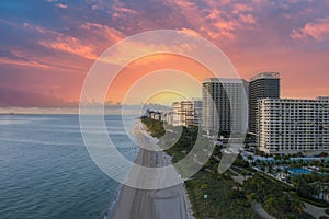 aerial shot of hotels, luxury condos and skyscrapers along the coastline at sunrise at Bal Harbour Beach, blue ocean water