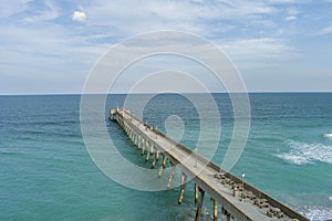 aerial shot of Johnnie Mercer\'s Fishing Pier with vast blue ocean water and people walking along the pier, blue sky