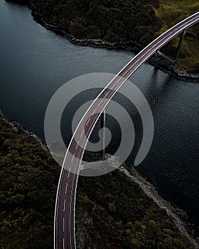 Aerial shot of Kylesku Bridge, a curved arch bridge spanning a scenic river photo