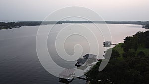 Aerial shot of a lake a green beach and lakehouses with a gorgeous skyline