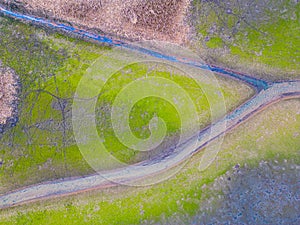 An aerial shot of the landscape with small lake surrounded by trees and field