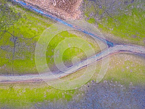 An aerial shot of the landscape with small lake surrounded by trees and field