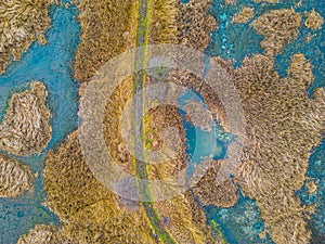 An aerial shot of the landscape with small lake surrounded by trees and field