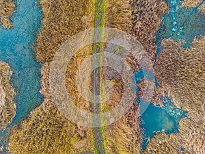 An aerial shot of the landscape with small lake surrounded by trees and field