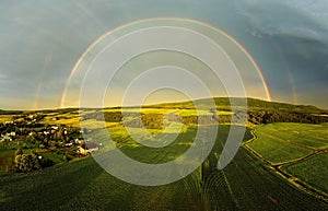 an aerial shot of a large field with a rainbow in the sky