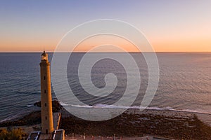 Aerial shot of a lighthouse on the shore of a sea during sunset