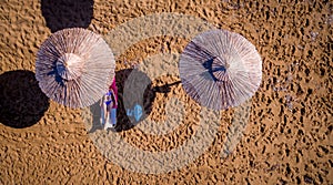 Aerial shot of a lone woman relaxing under an umbrella on the beach.