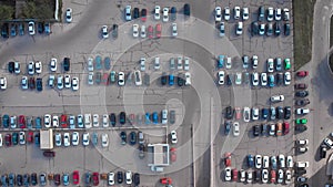 Aerial shot, lots of cars downstairs. Parking of a shopping or business center. A lot of occupied places. Motorization