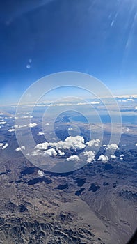 an aerial shot for majestic mountain ranges covered in snow and powerful clouds and blue sky in California