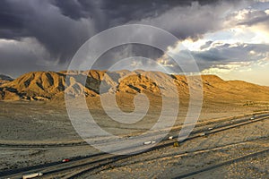 an aerial shot of majestic mountain ranges in the desert at sunset with cars and trucks driving on the highway in Yermo California photo