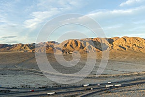 an aerial shot of majestic mountain ranges in the desert at sunset with cars and trucks driving on the highway in Yermo California photo
