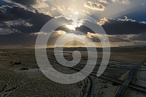 an aerial shot of majestic mountain ranges in the desert at sunset with cars and trucks driving on the highway in Yermo California photo