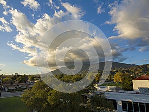 Aerial shot of majestic mountains with powerful clouds and blue sky with homes, apartments and lush green trees in Monrovia photo