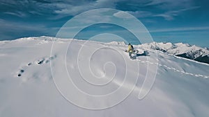Aerial shot male active sports man climbing on top of snow mountain making snowboarding