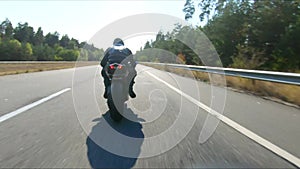 Aerial shot of man riding fast on modern sport motorbike at highway during summer day. Motorcyclist racing his