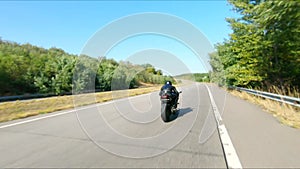 Aerial shot of man riding fast on modern sport motorbike at highway during summer day. Motorcyclist racing his