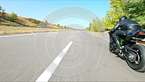 Aerial shot of man riding fast on modern sport motorbike at highway during summer day. Motorcyclist racing his