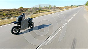 Aerial shot of man riding fast on modern sport motorbike at highway during summer day. Motorcyclist racing his
