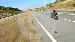 Aerial shot of man riding fast on modern sport motorbike at highway during summer day. Motorcyclist racing his